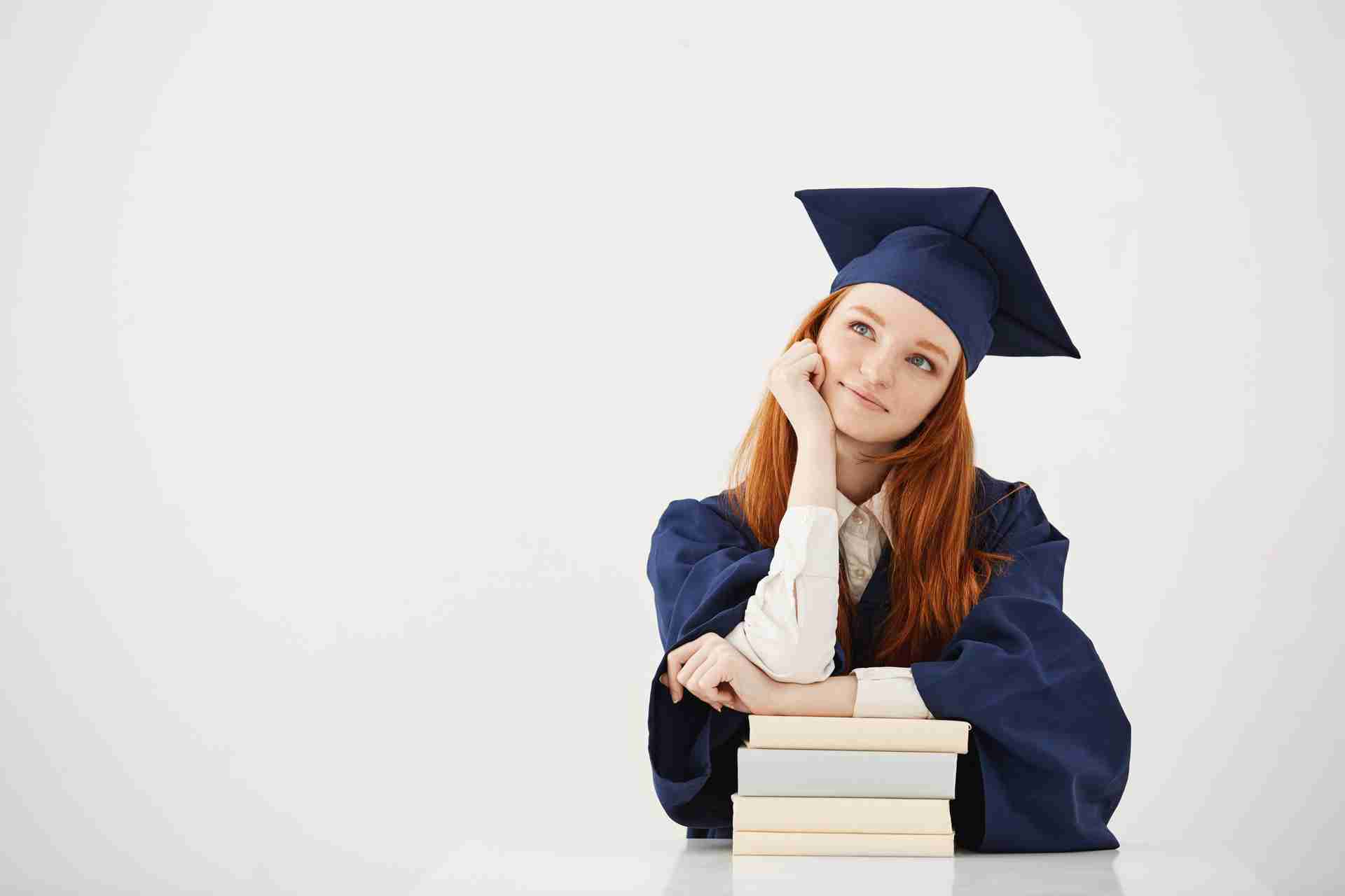 dreamy-graduate-woman-smiling-thinking-sitting-with-books.jpg